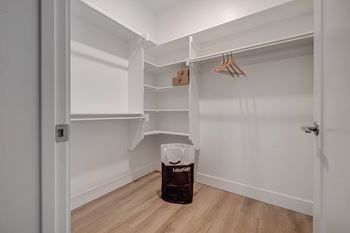 A laundry bag sits on a wooden floor in a white room.